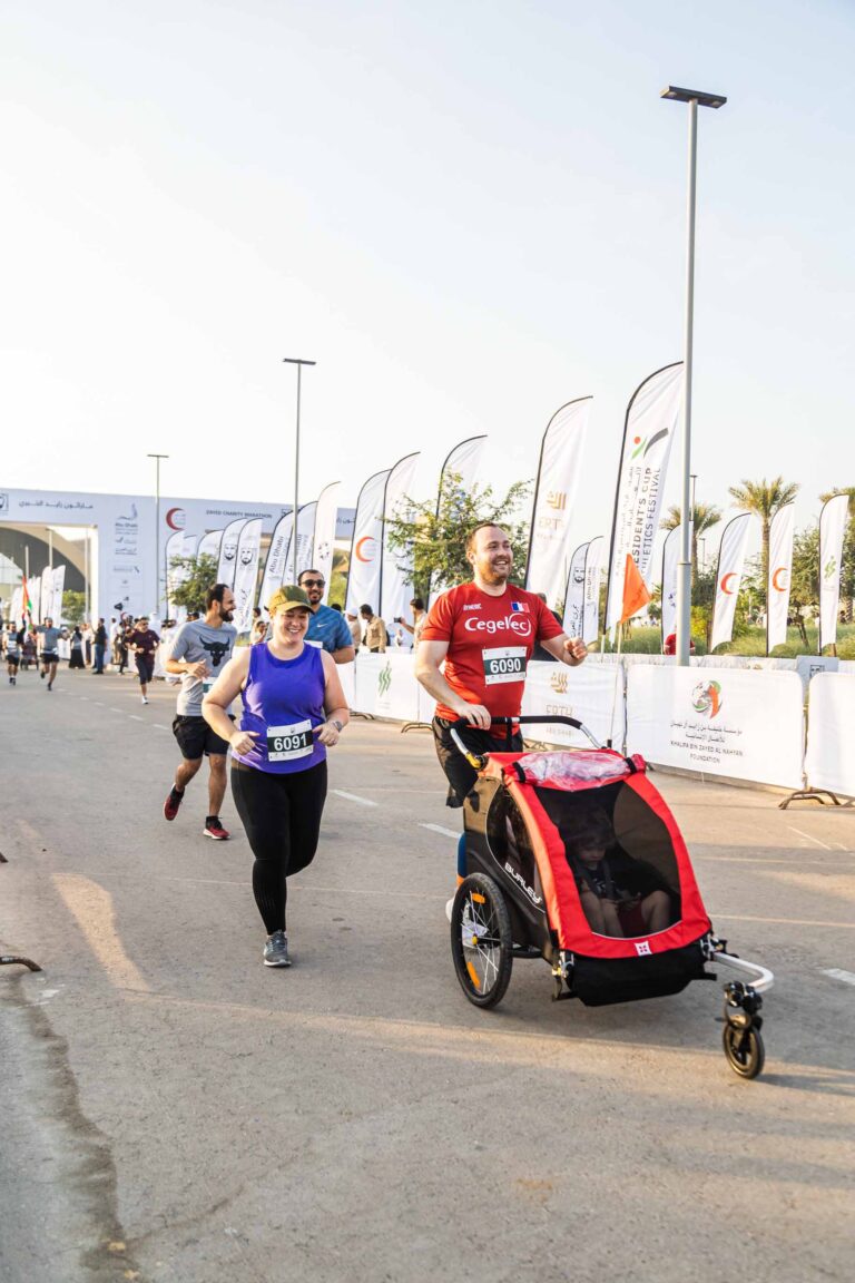 Parents running with baby stroller at Zayed Charity Marathon Abu Dhabi 2022